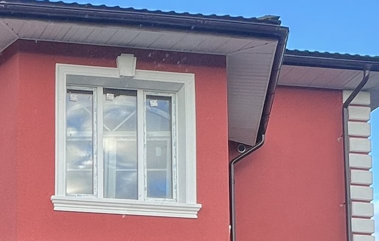 Окно с белым наличником и белые русты на насыщенном красном фасаде